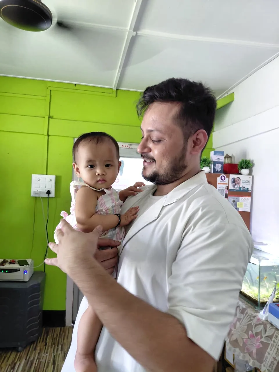 Dr. Dhyan Saharia holding a smiling baby at the clinic